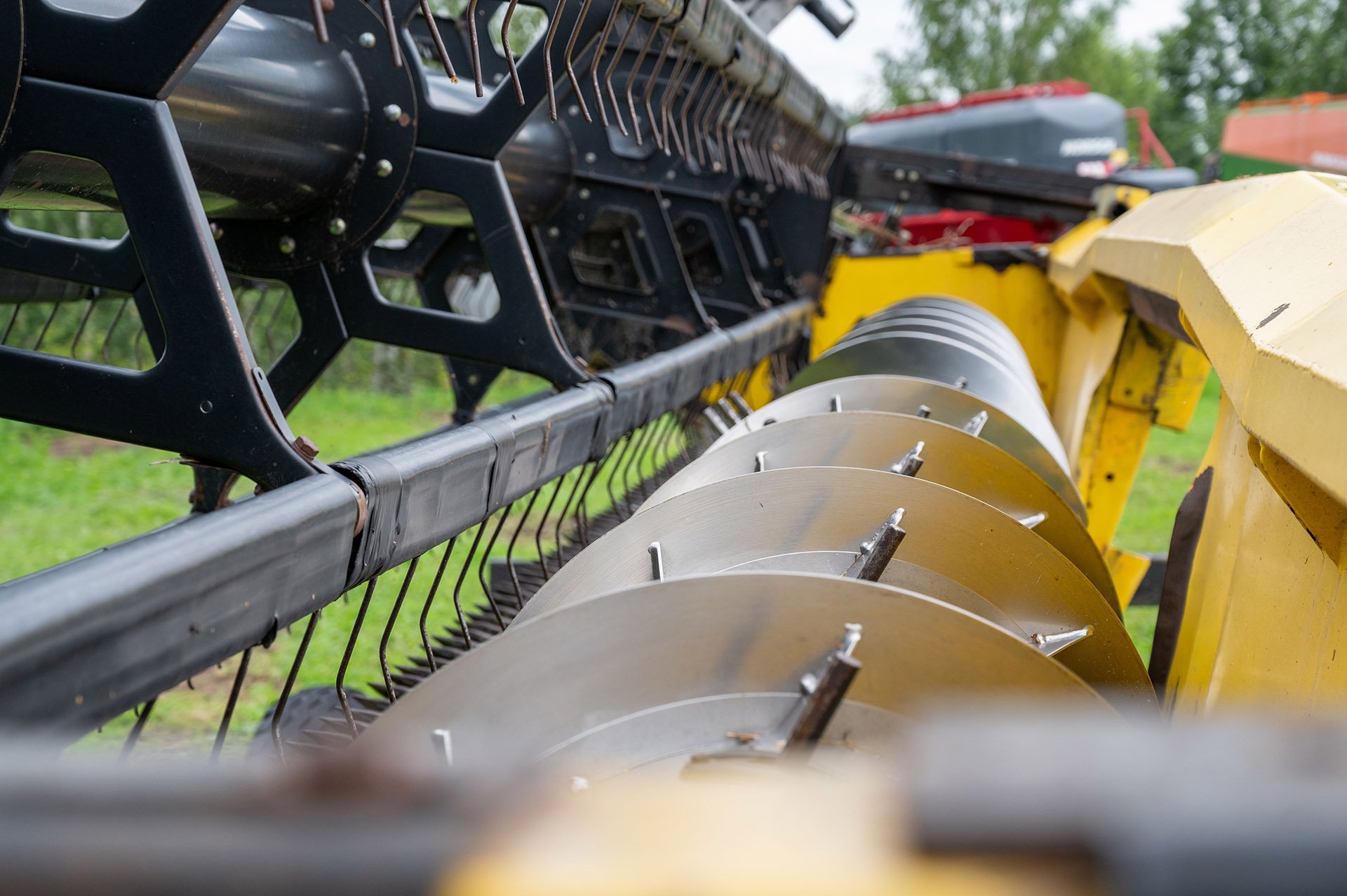 Close-up of agricultural machinery with metallic discs and a guard, set against a green background, indicating field readiness.